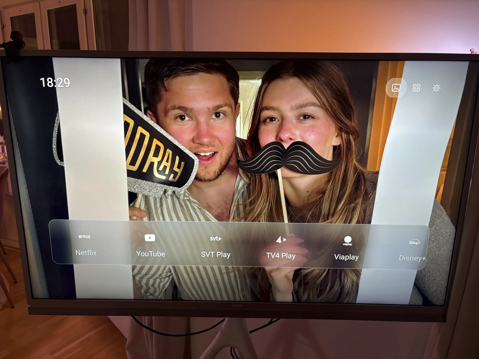 Philips Android TV med egen startskärm efter att bloatware tagits bort: helskärmsfoto, klocka och ett dock med Netflix, YouTube, SVT Play, TV4 Play, Viaplay och Disney+.